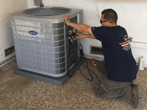 Hand adjusting a thermostat on wal air conditioning
